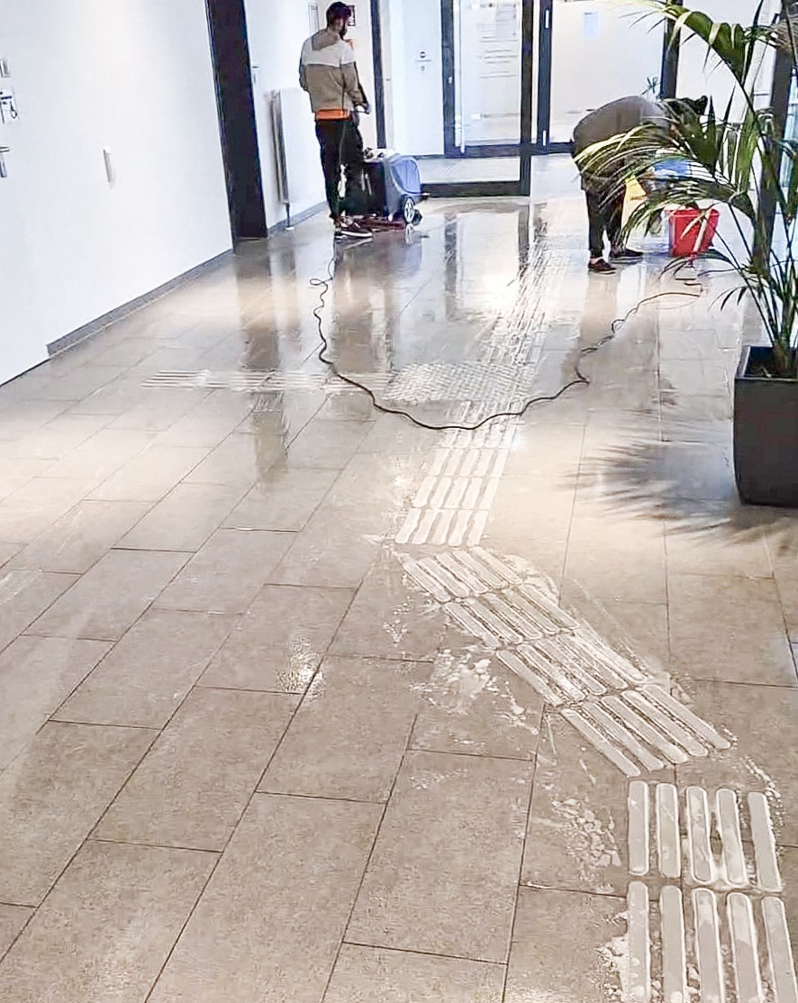 Zwei Mitarbeiter bei der Bodenreinigung eines Eingangsbereichs